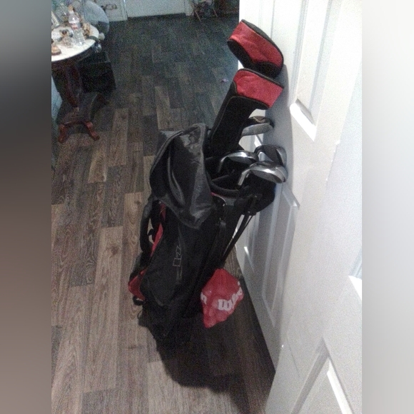 Golf caddy with clubs and golf balls also a couple of pins.